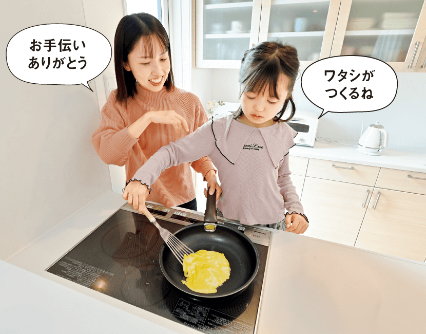 Yさんファミリーの長女のYちゃんがIHクッキングヒーターでホットケーキを焼き、長女のYちゃんが「ワタシがつくるね」、ママが「お手伝いありがとう」と言っている画像